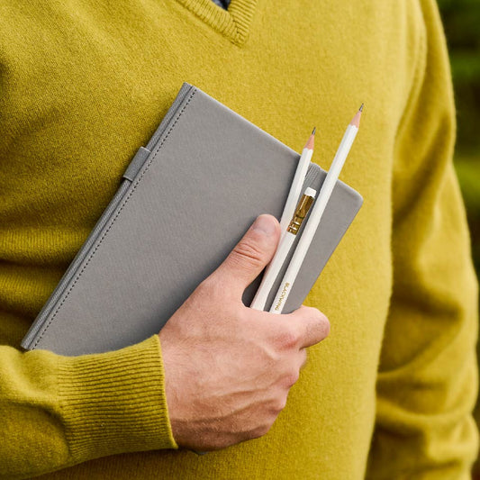 Hand holding Blackwing pencils and notebook