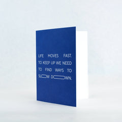blue greeting card featuring a text imprint that says "life moves fast. to keep up we need to find ways to slow down." Inside of card is white.