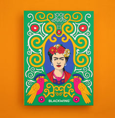 A colorful Frida Kahlo stationery box set featuring colors of yellow and white swirls, with two and orange pink birds at the bottom and the text BLACKWING, shown against a solid orange background.