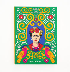 A colorful gift set box featuring a stylized portrait of Frida Kahlo framed by ornate yellow and white swirls on a green background, with two pink and orange birds and the text BLACKWING at the bottom, shown against a plain white background.