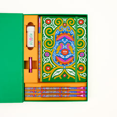 Colorful Frida Kahlo stationery gift set arranged inside a green box on a white background. The set includes a decorative notebook with Frida Kahlo's artwork, several matching patterned pencils, a white sharpener with a floral and vine illustration, and a pink point guard.