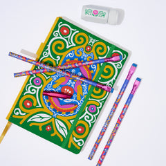 A colorful decorative notebook with a green cover and ornate multicolor swirl and floral patterns, shown with four matching patterned pencils, a pink metallic point guard, and a white eraser on a clean white background.