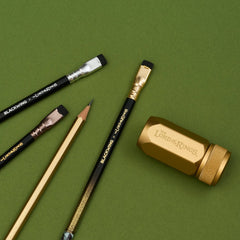 The Lord of the Rings Blackwing pencils next to a gold sharpener on a green background
