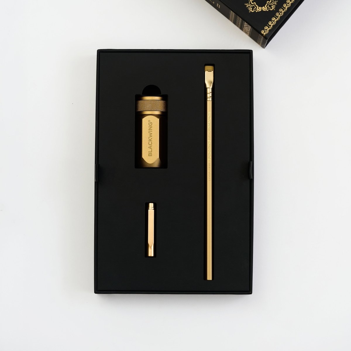 Blackwing x Lord of the Rings gold sharpener, gold point guard, and gold pencil in a black package on a white background
