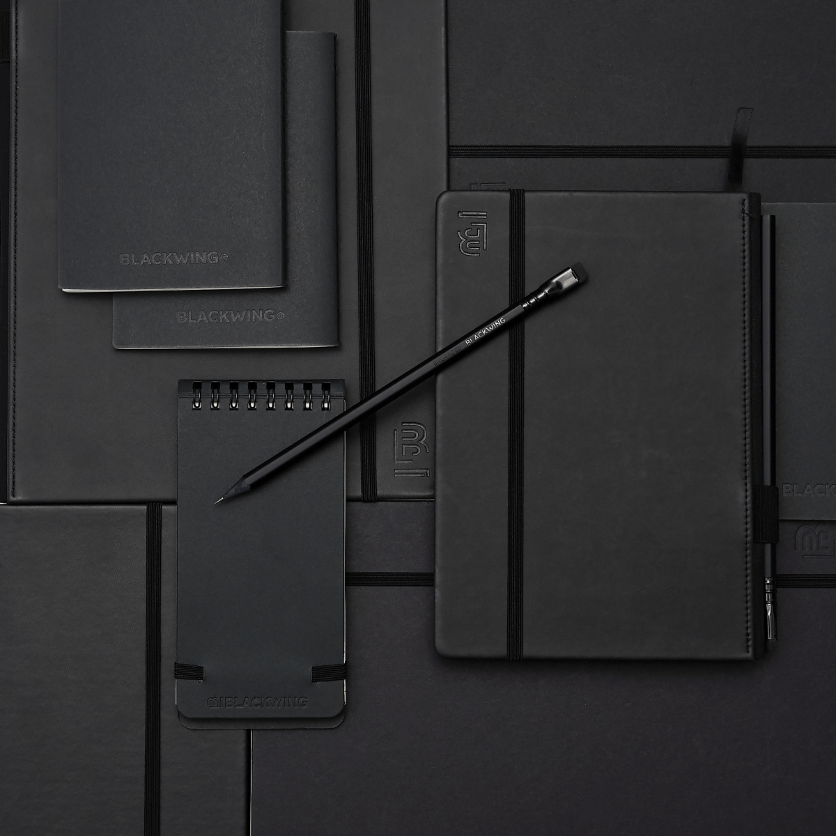 black pencil on top of black notebooks and notepads