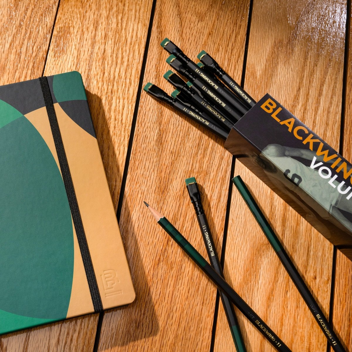 Blackwing Volume 11 Bill Russell Pencils and notebook on a wood floor