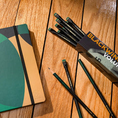 Blackwing Volume 11 Bill Russell Pencils and notebook on a wood floor