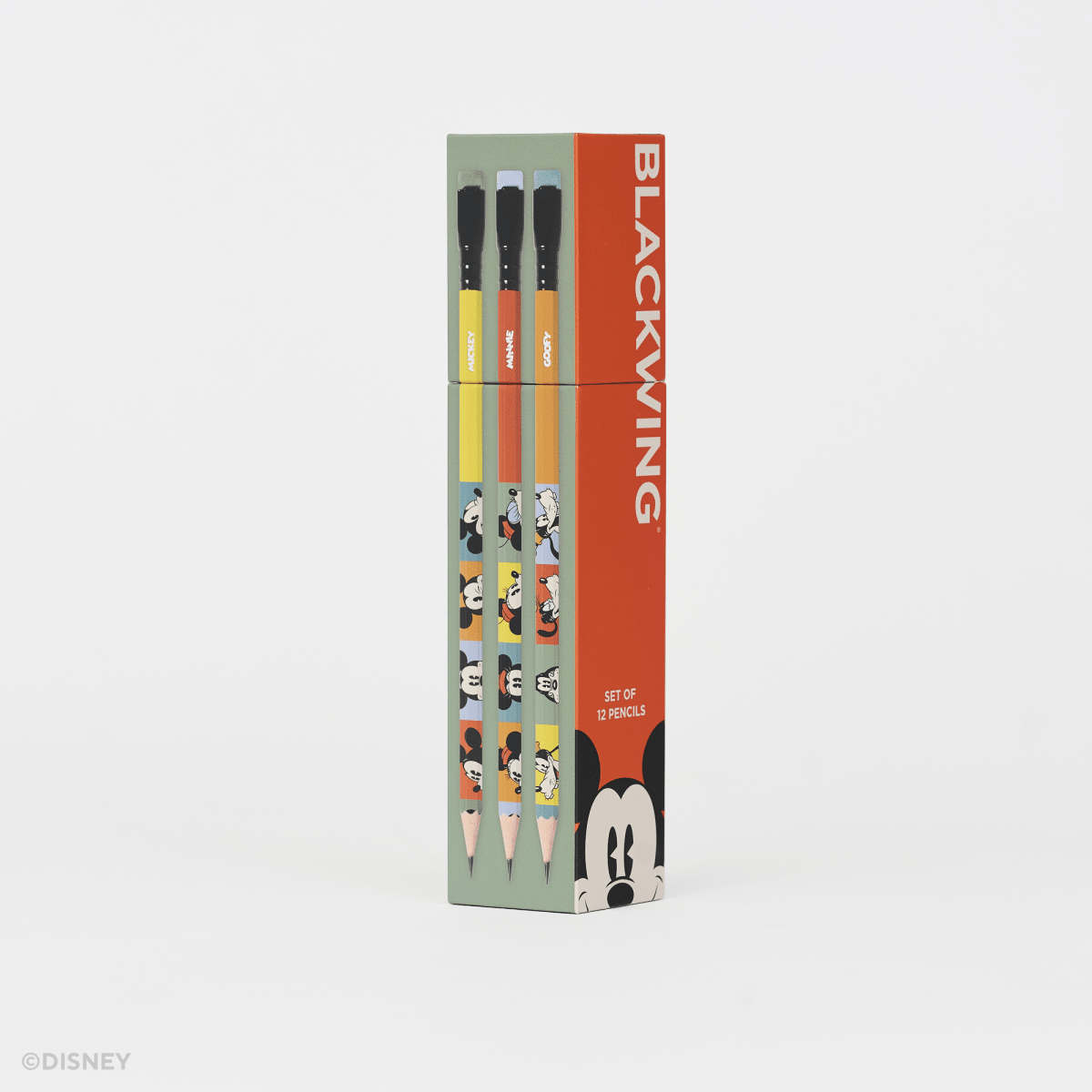 A boxed set of Disney Blackwing pencils standing upright on a clean white background. The packaging is mint green and bright orange-red, with printed character illustrations and the word BLACKWING prominently visible.