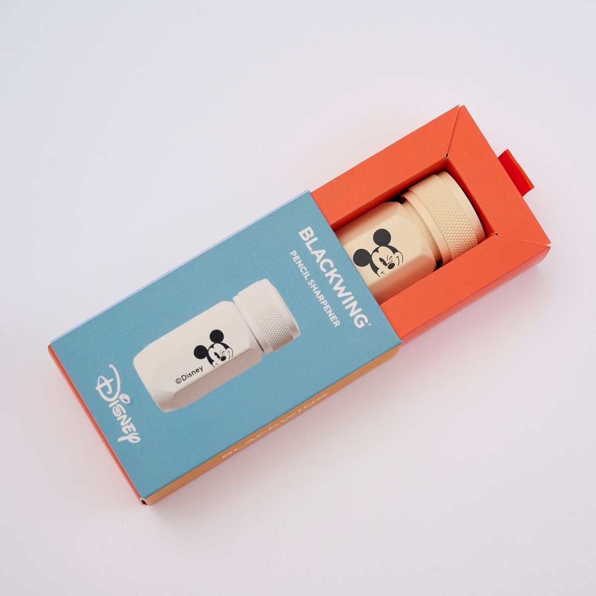 Disney Blackwing Pencil Sharpener in a red and blue rectangular box, featuring a beige pencil sharpener with a black Mickey Mouse head graphic.