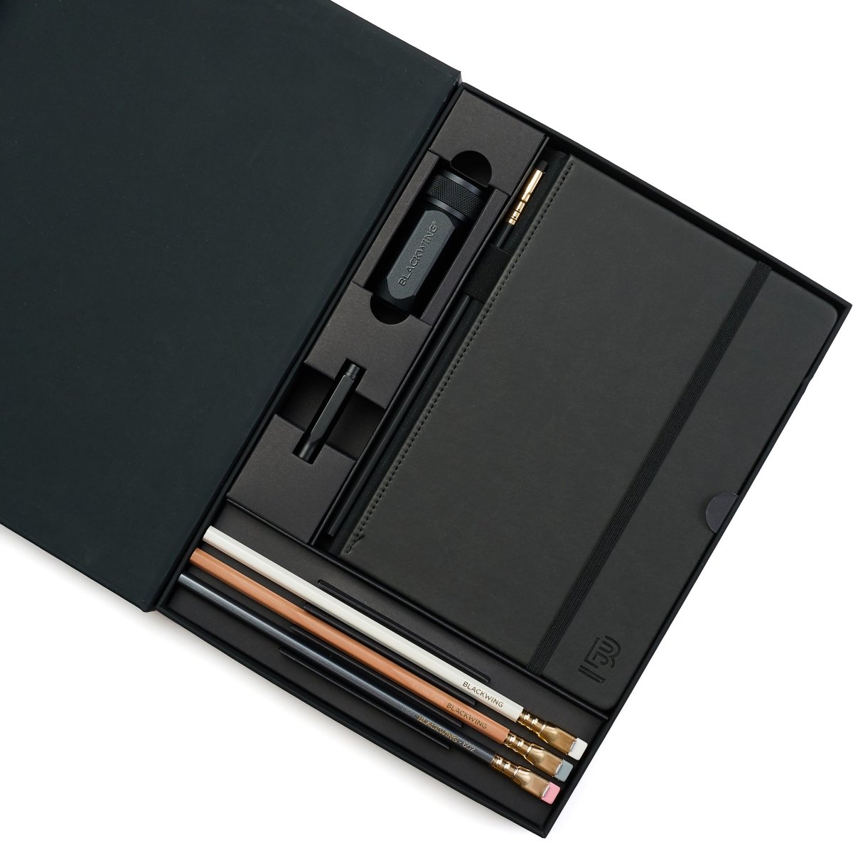 Black stationery set with graphite pencils, notebook, pencil guard, and one-step sharpener.