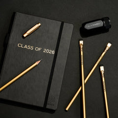 Graduation present for class of 2026, includes a black notebook, four gold pencils, a black sharpener, and a gold pencil point guard