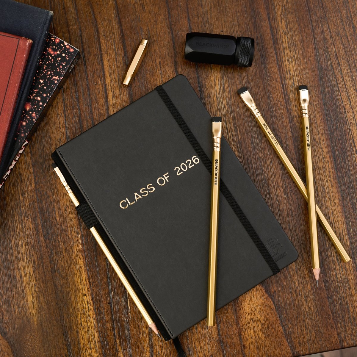 Graduation stationery gift set for class of 2026, includes a black notebook, four gold pencils, a black sharpener, and a gold pencil point guard