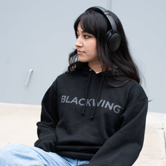 Person listening to music, wearing a Blackwing hoodie