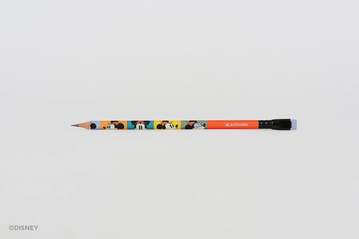 A Disney branded Blackwing pencil with colorful Minnie Mouse illustrations and a red-orange barrel, shown horizontally on a plain light gray background.