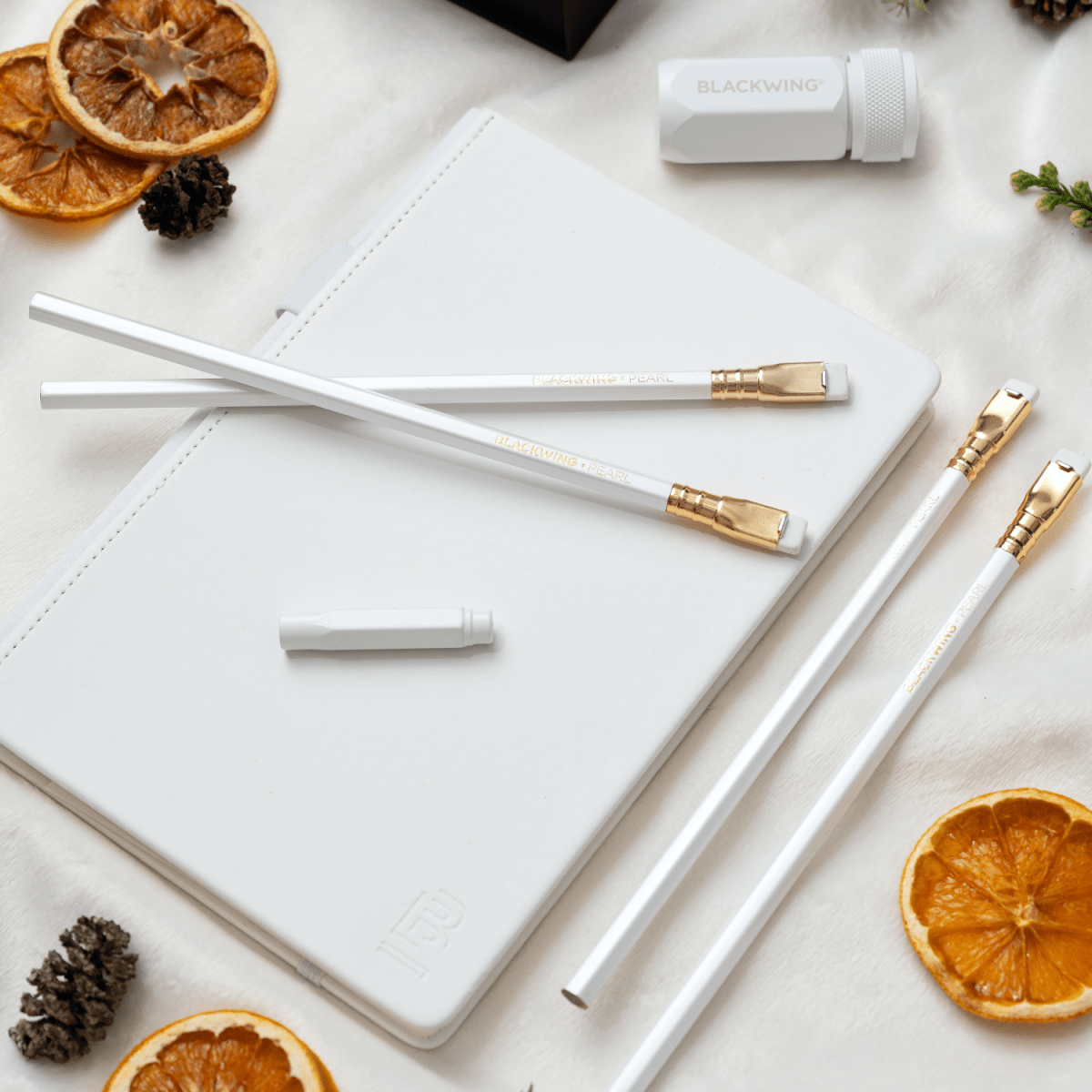 Blackwing winter notebook essentials set includes a white one-step sharpener, white pencil guard, 4 pearl pencils, and a white slate notebook