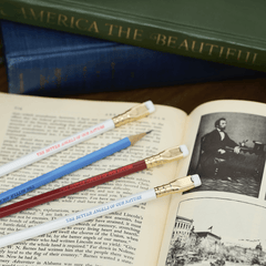 4 pencils (2 white, 1 blue, 1 red) lay across an open book with a photo of Abraham Lincoln