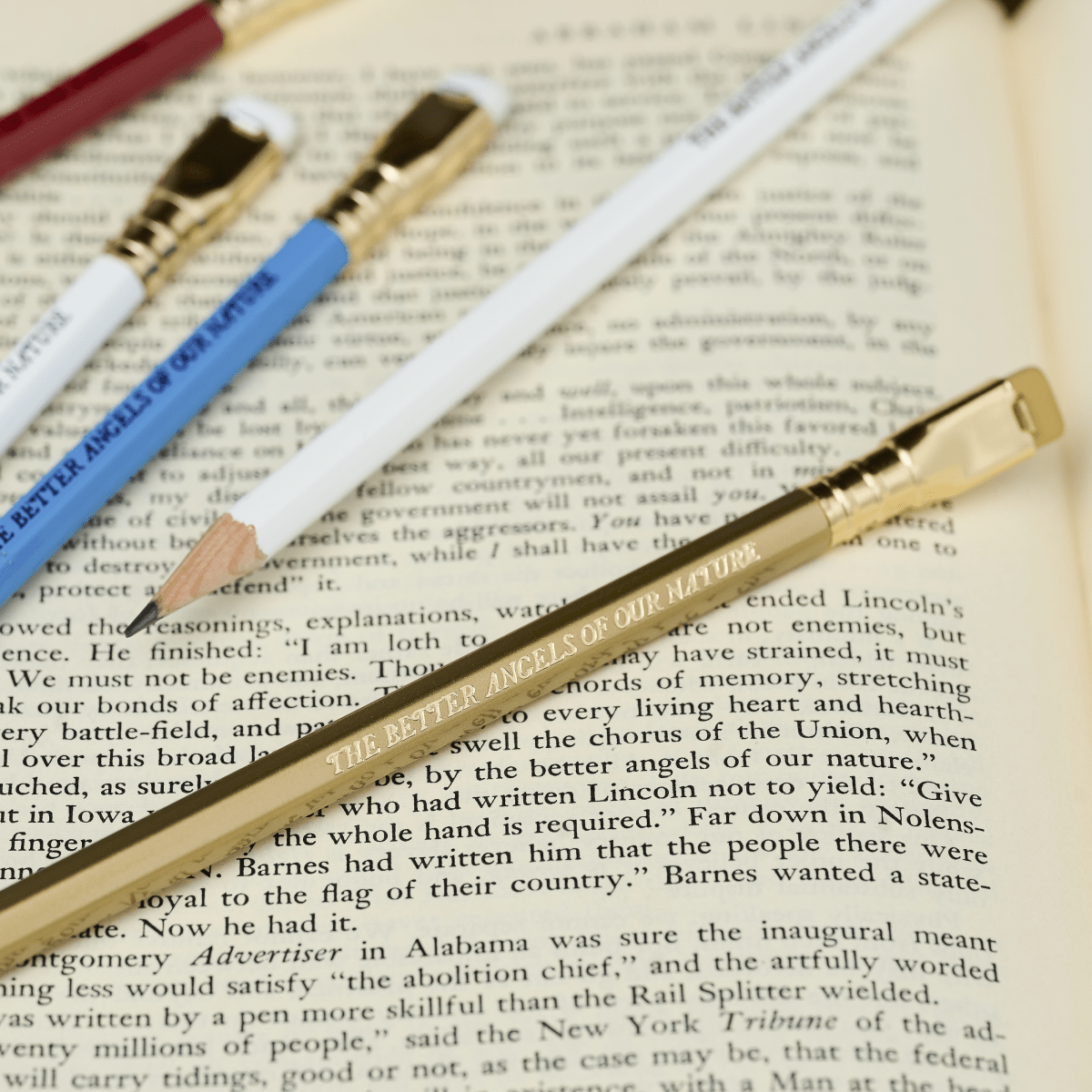 Blackwing pencils in red, white, blue, and gold, each with imprint 'THE BETTER ANGELS OF OUR NATURE' on top of an open book