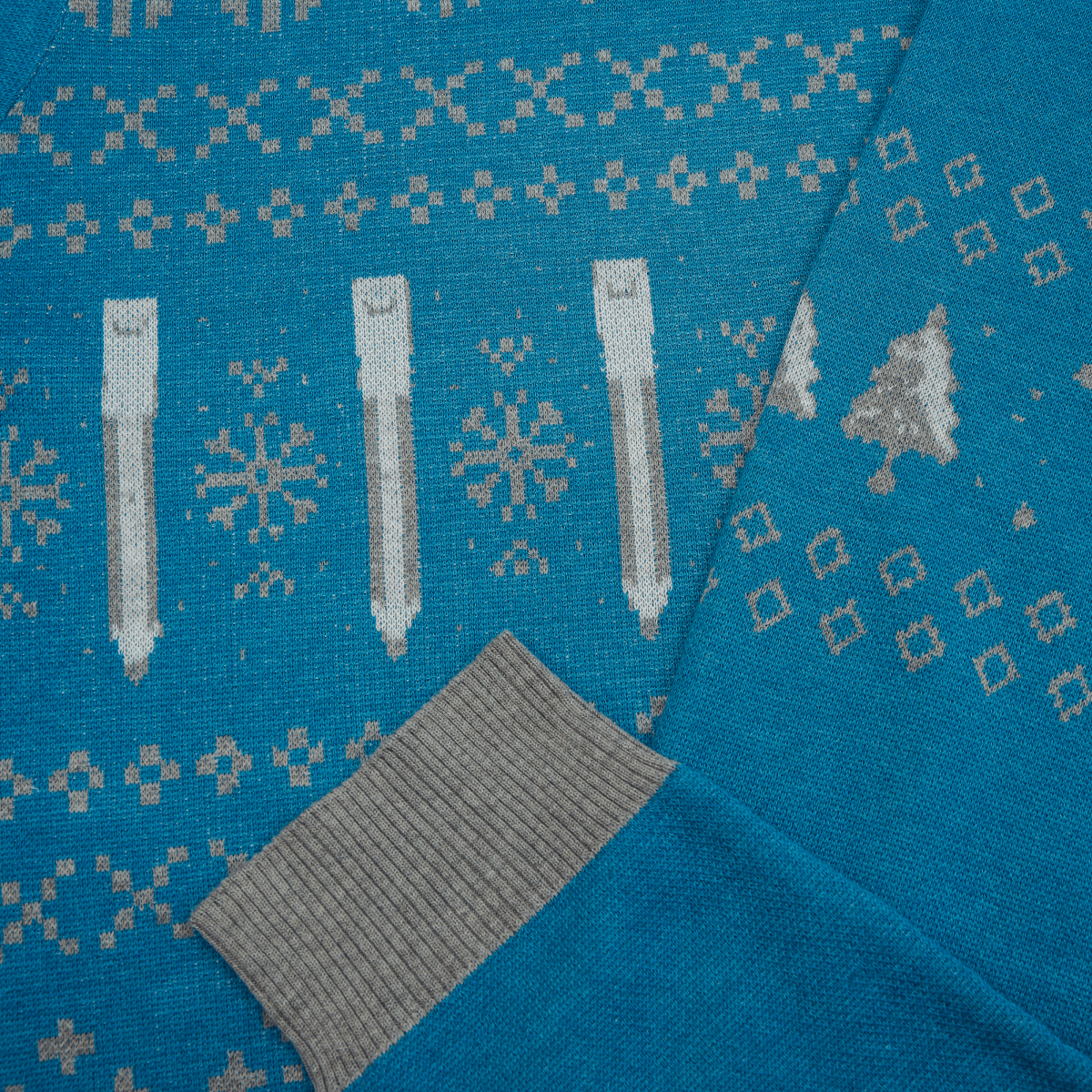 Blue sweater with winter pattern featuring trees, snowflakes, and pencils.