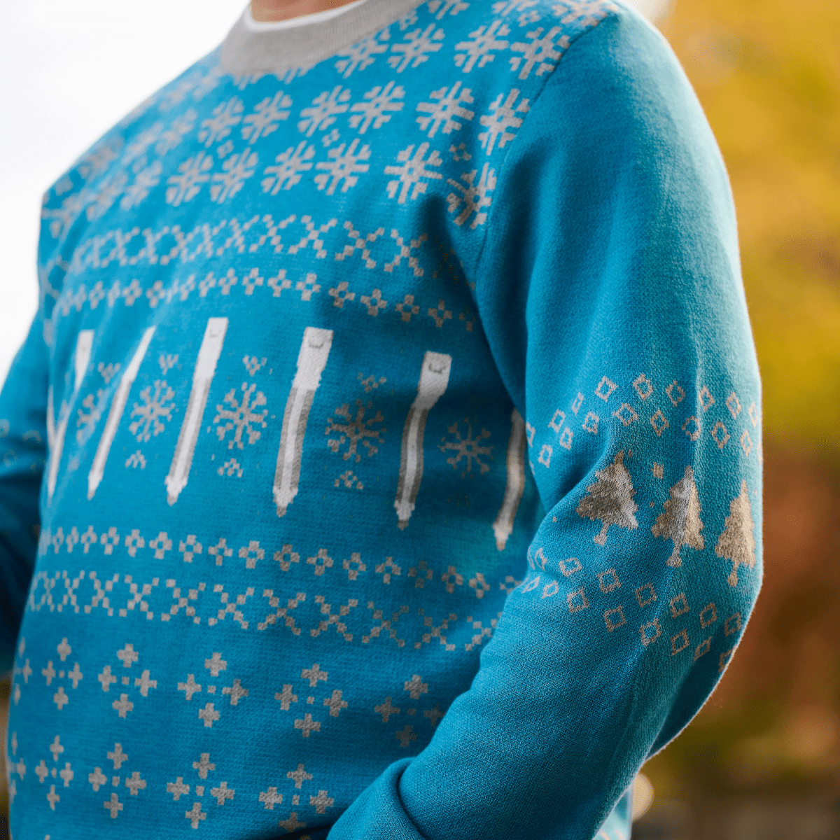 Blue sweater with white and grey patterns worn by a person outdoors.