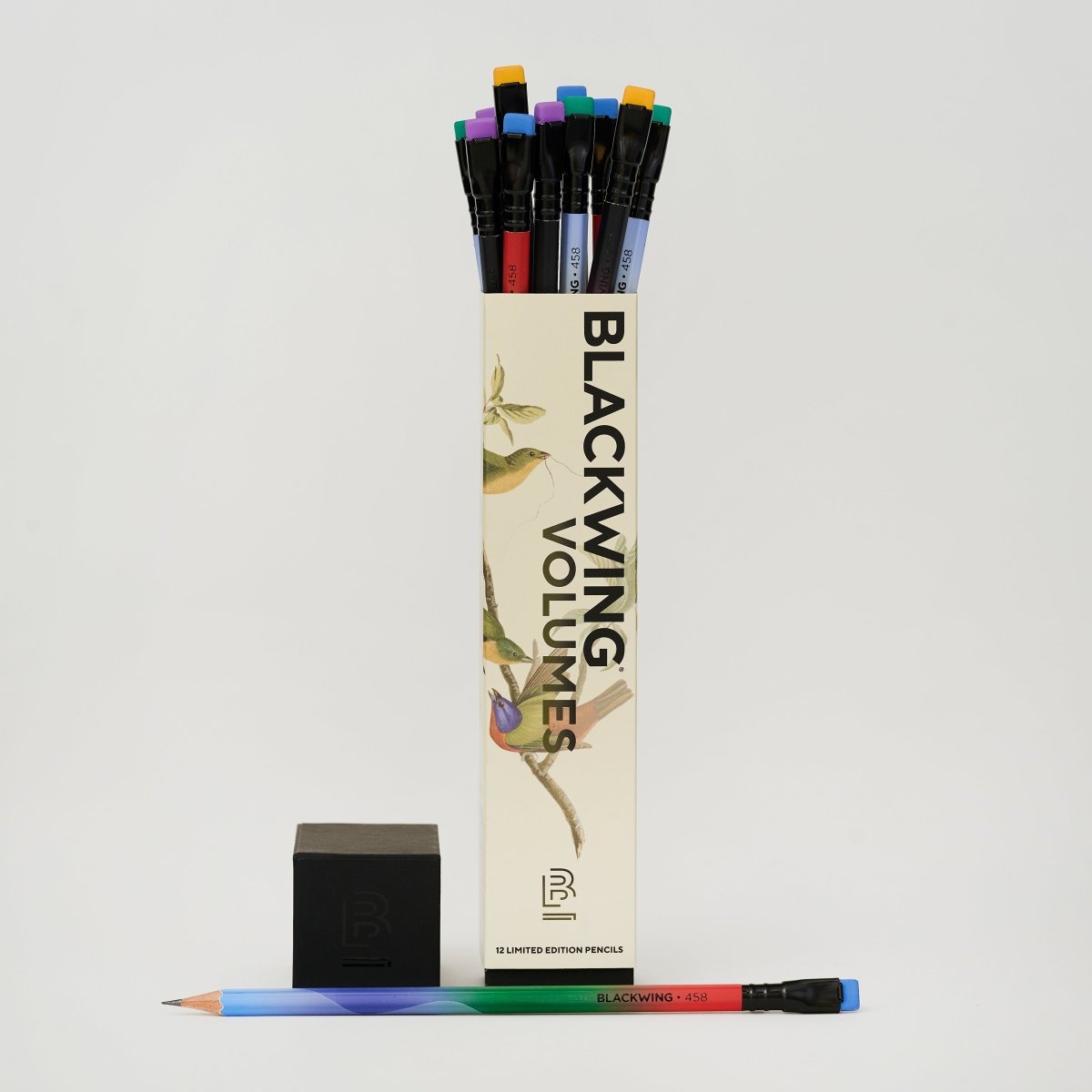 Blackwing Volumes pencil box with bird illustration, lid off to the side with tops of colorful pencil erasers poking out and one pencil laying horizontal at the base of the box