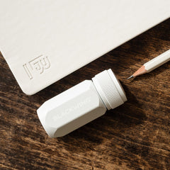 Blackwing One-Step Long Point Sharpener in white, next to a pearl pencil and white slate notebook