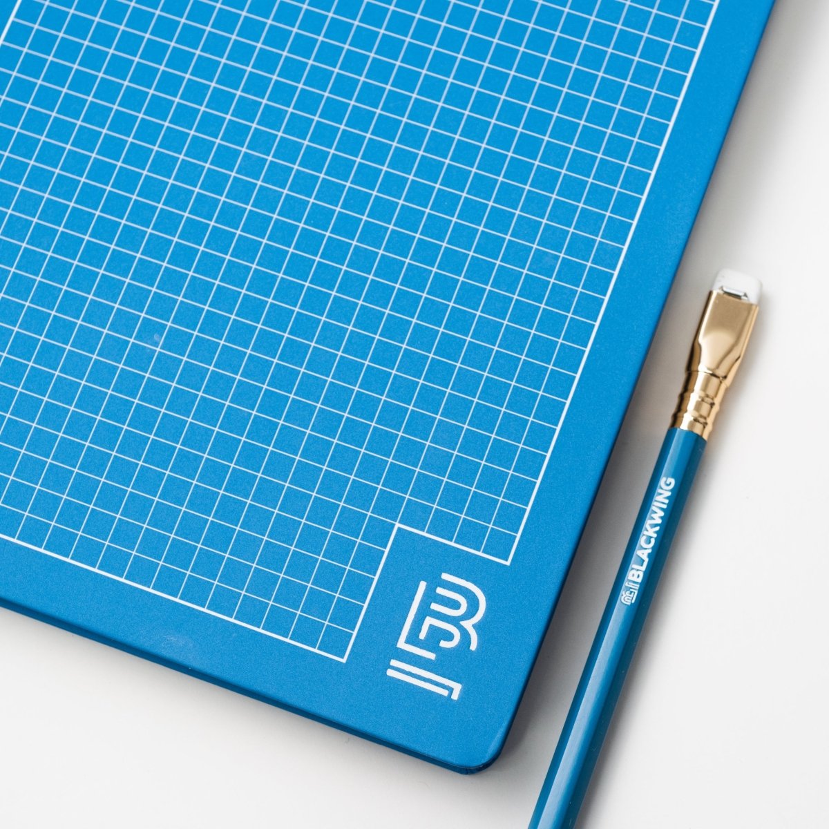 Blackwing blue notebook with white grid and blue pencil with white Blackwing imprint, gold ferrule, and white eraser