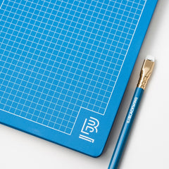 Blackwing blue notebook with white grid and blue pencil with white Blackwing imprint, gold ferrule, and white eraser