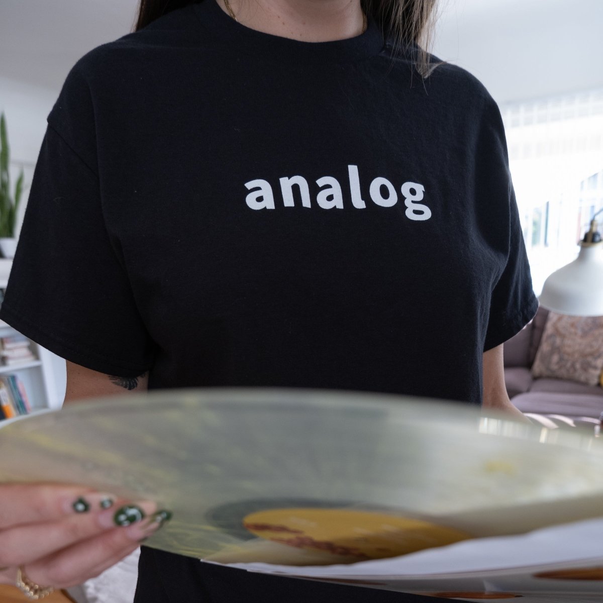 person wearing a black cotton t-shirt with the word analog on it