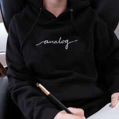 person wearing black hoodie with white "analog" cursive text 